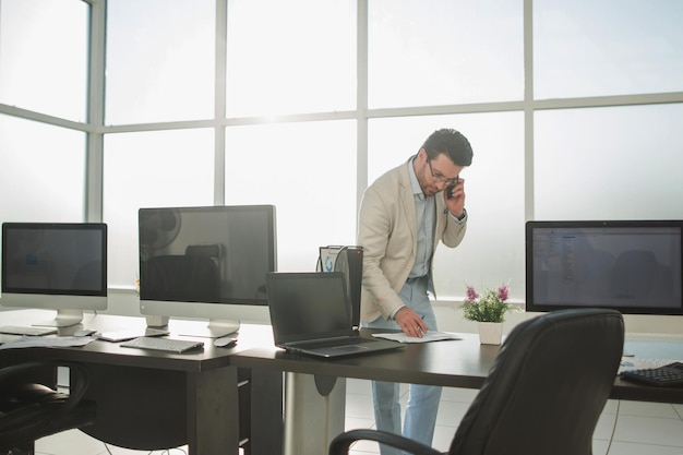 Empresario trabajando en una calculadora de pie en una foto de oficina brillante con espacio de copia