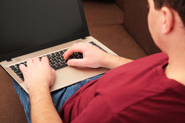 Empresario trabajando en casa con una computadora portátil y tomando café en el sofá