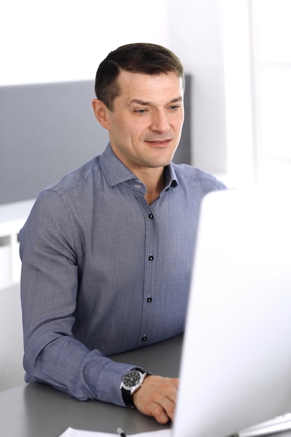 Empresario trabajando con computadora en la oficina moderna. Captura de cabeza de empresario masculino o director de empresa en el lugar de trabajo. Concepto de negocio.