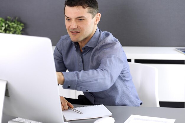 Empresario trabajando con computadora en la oficina moderna. Captura de cabeza de empresario masculino o director de empresa en el lugar de trabajo. Concepto de negocio.