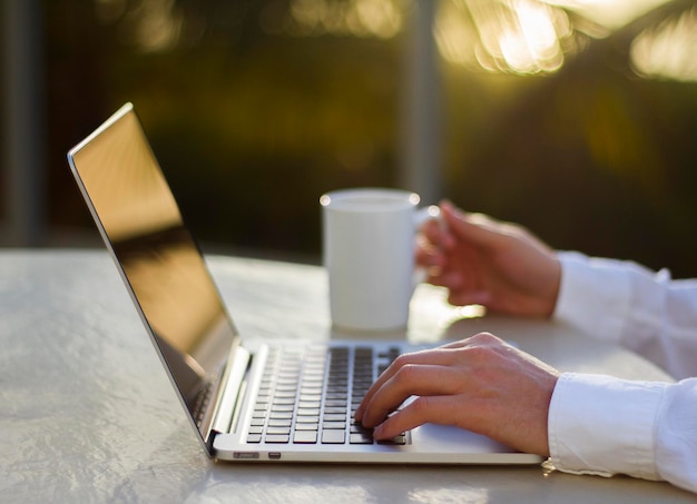 Empresario trabajando con laptop y taza de café al atardecer