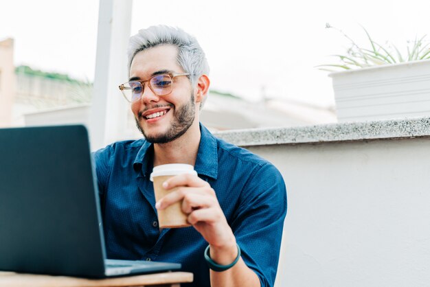 Empresario trabajando en un portátil y tomando café al aire libre