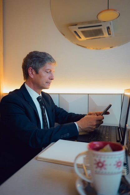 Foto empresario trabajando remotamente en una cafetería mirando su teléfono móvil