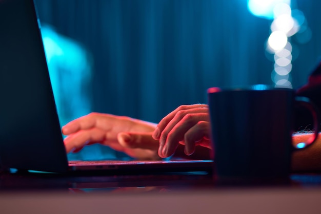 Empresario trabajando remotamente escribiendo en el teclado de una computadora portátil sobre luces de neón trabajando en línea