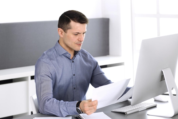 Empresário trabalhando com computador no escritório moderno. Tiro na cabeça do empresário masculino ou diretor da empresa no local de trabalho. Conceito de negócios.