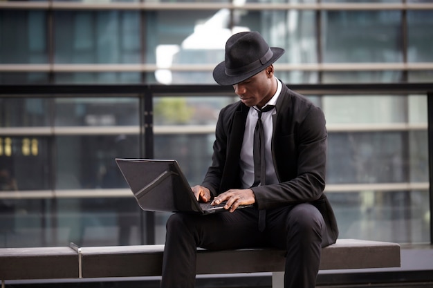 Empresário, trabalhando com dispositivos móveis e laptop em ambiente urbano