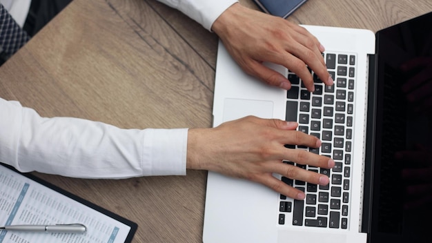 Empresário trabalhando com laptop e documentos sentados na mesa do escritório