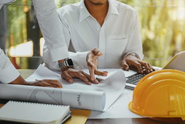 Empresário trabalhando em equipe discutindo trabalho de dados e tablet laptop com projeto arquitetônico no canteiro de obras na mesa