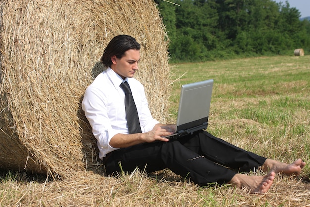 Empresário, trabalhando em um laptop enquanto inclinando-se para um fardo