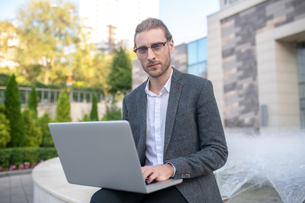 Empresário trabalhando em um laptop fora do prédio