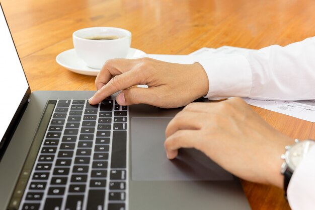 Empresário trabalhando no laptop com papelada na mesa