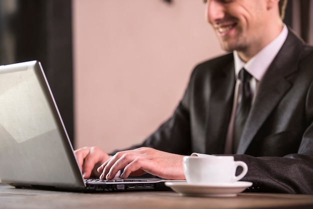 Empresário, trabalhando no laptop com uma xícara de café.