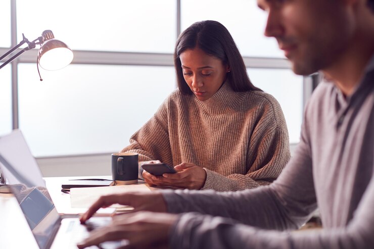 Foto empresário trabalhando no laptop na mesa colaborando com colega feminina usando telefone celular