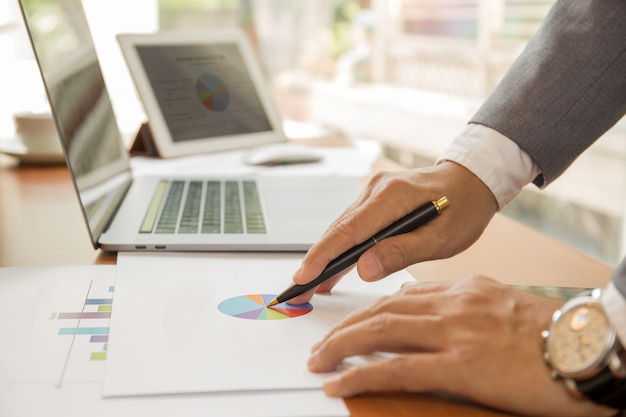 Empresário, trabalhando no plano financeiro com o laptop na mesa