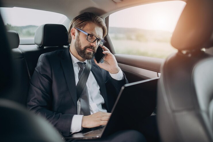 Empresario en traje conversando en el móvil en el coche