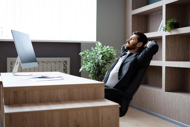 Empresario con traje elegante sentado en el escritorio de la computadora en la oficina