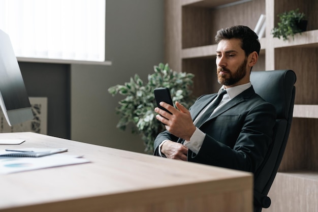 Empresario con traje elegante sentado en el escritorio de la computadora en la oficina