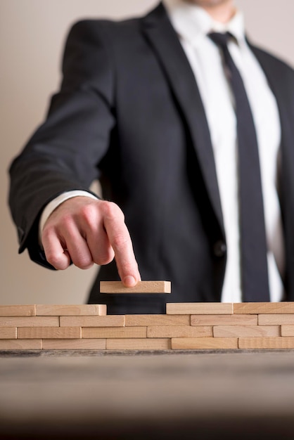 Empresario en traje de negocios colocando bloques de madera en la mesa