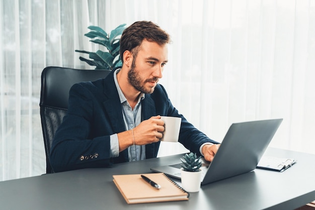 Empresario en traje negro trabajando en una computadora portátil en su escritorio de trabajo Entidad