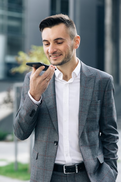 Empresário usa smartphone para enviar mensagens de voz ao ar livre no centro da cidade