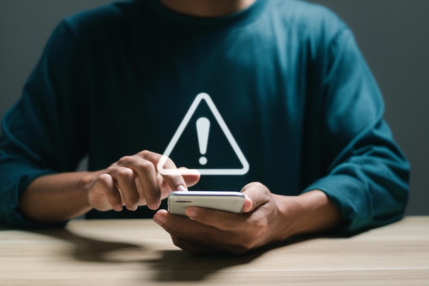 Empresário usa telefone móvel inteligente com sinal de alerta virtual para cautela no investimento aviso de situação econômica riscos de investimento empresarial