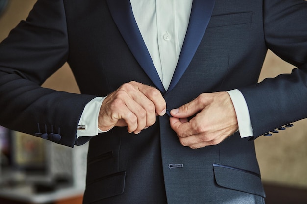 Empresário usa um casaco de mãos masculinas fechadas noivo se preparando de manhã antes da cerimônia de casamento