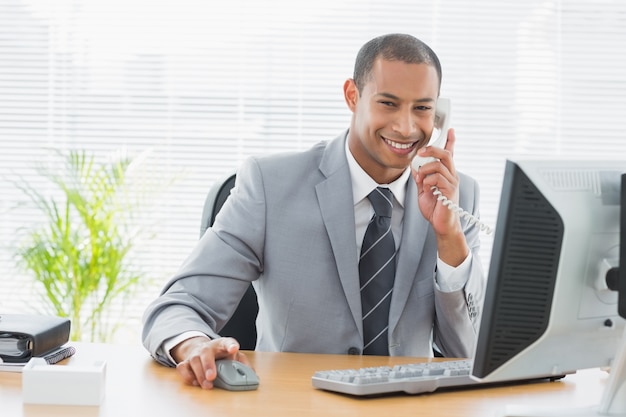 Empresário usando computador e telefone na mesa de escritório