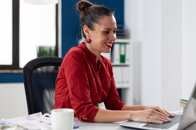 Empresario usando una computadora portátil en la puesta en marcha de la oficina de la empresa en el lugar de trabajo escribiendo información del proyecto ...