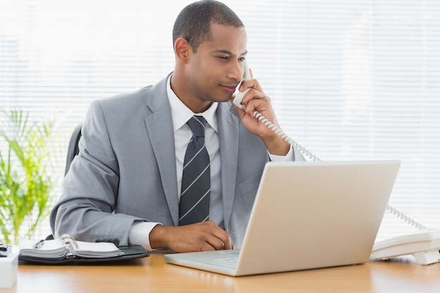 Empresário usando laptop e telefone na mesa