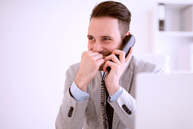 Empresário usando laptop enquanto fala ao telefone no escritório