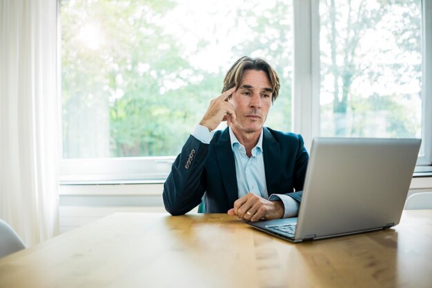 Empresário usando laptop na mesa no escritório