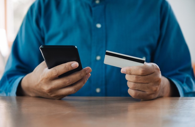 Empresário usando smartphone e cartão de crédito para compras online em casa com espaço de cópia