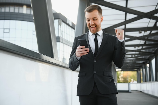 Empresário usando smartphone em passarela coberta