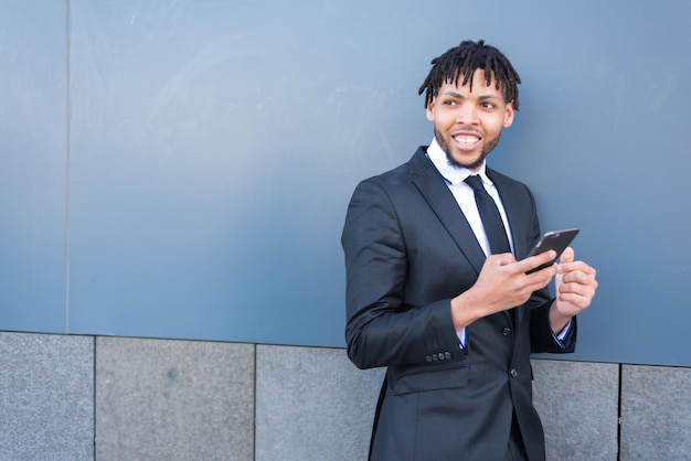 Empresário usando smartphone na parede azul da rua