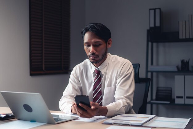 Empresário usando smartphone para verificar o relatório enquanto analisa as finanças e a contabilidade do projeto