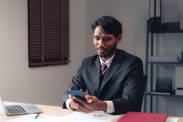 Empresário usando smartphone para verificar o relatório enquanto analisa as finanças e a contabilidade do projeto