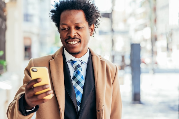 Empresario usando su teléfono móvil mientras camina al aire libre en la calle