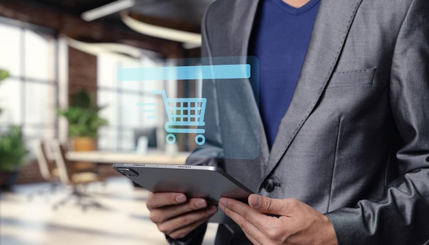Empresario usando tableta con icono de carrito de compras en la oficina moderna