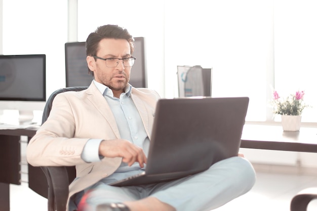 Empresário usando um laptop sentado em seu Deskpeople e tecnologia