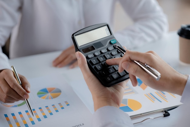 Empresário usando uma calculadora para calcular números nos documentos financeiros de uma empresa, ele está analisando dados financeiros históricos para planejar como aumentar o conceito financeiro da empresa