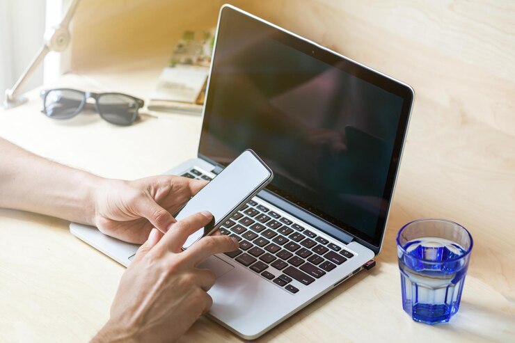 Foto empresario utilizando su smartphone en el fondo de la computadora portátil