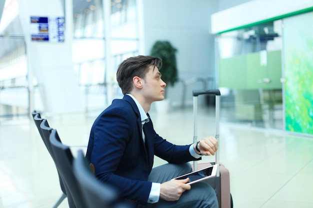 Empresário, verificando o tempo e usando o tablet no aeroporto.