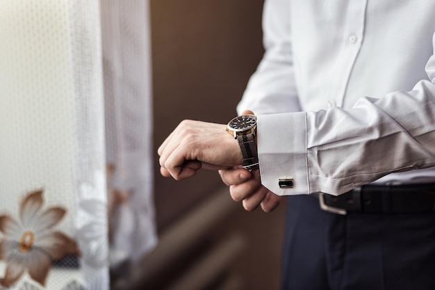 Empresário verificando o tempo em seu relógio de pulso homem colocando relógio no noivo se preparando de manhã antes da cerimônia de casamento