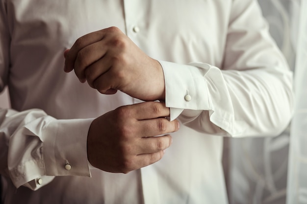 Empresário veste camisa branca, mãos masculinas closeup, noivo se preparando a manhã antes da cerimônia de casamento