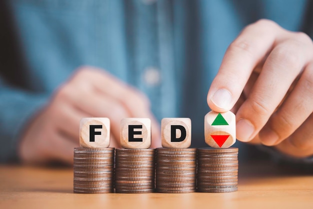 Empresario volteando la flecha hacia arriba y hacia abajo con la FED en el apilamiento de monedas para aumentar la reserva federal y disminuir el control de la tasa de interés que afecta el concepto de crecimiento económico de Estados Unidos y el mundo