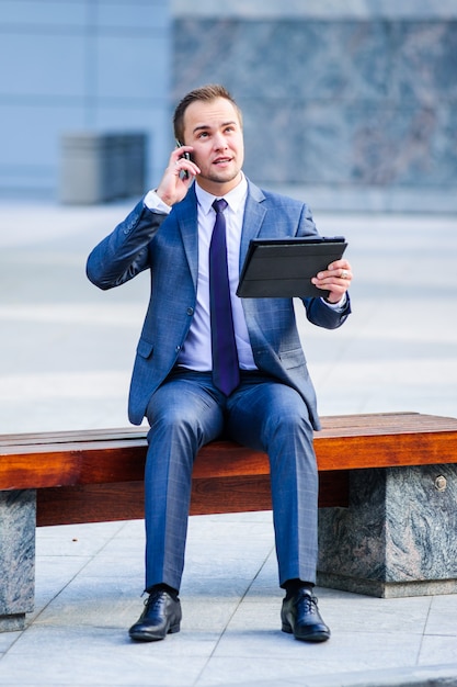 El empresario Yang trabaja con tablet PC al aire libre.