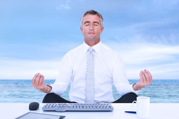 Empresario zen meditando en posición de loto contra la escena de la playa