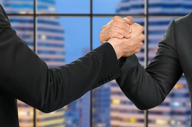 Foto empresarios amistosos se dan la mano. socios & # 39; apretón de manos en el fondo de la megalópolis. la ciudad espera a sus líderes. gente confiable y segura.