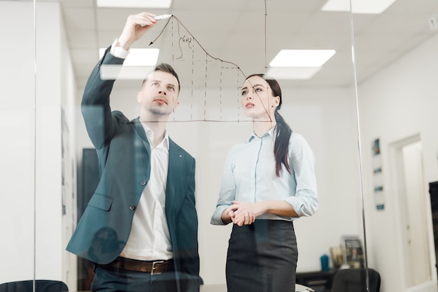 Empresarios analizando gráfico en pared de vidrio