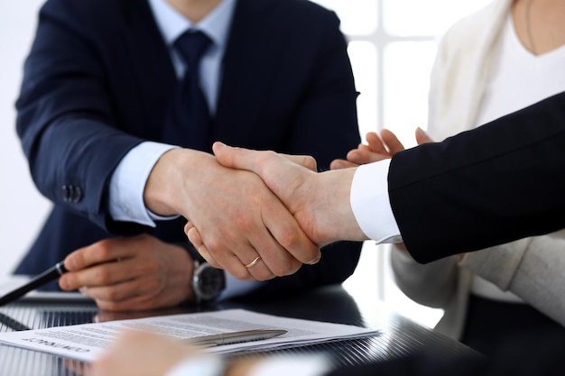 Empresários apertando as mãos após a assinatura do contrato na mesa de vidro no escritório moderno